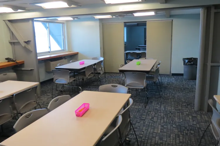 A classroom with rectangle tables and chairs around them