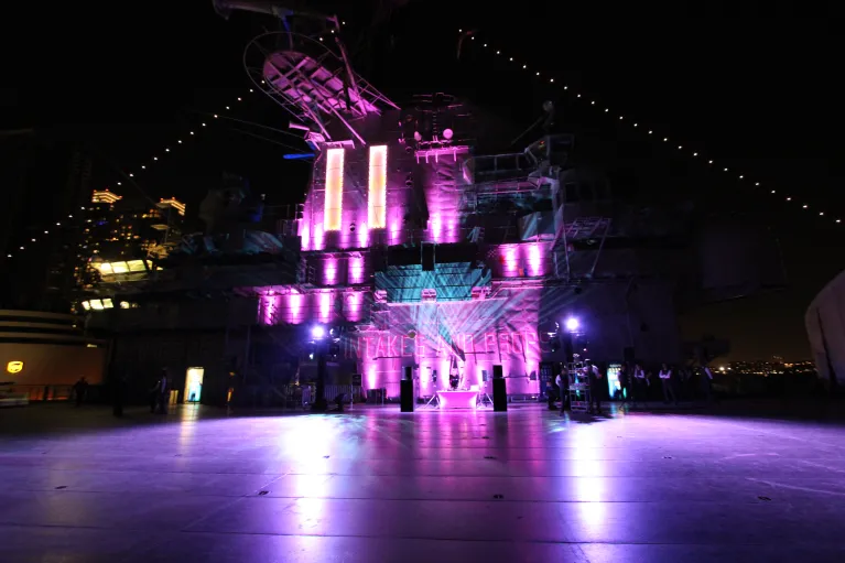 DJ set at the Center of the Flight Deck Island with string lights and purple uplighting