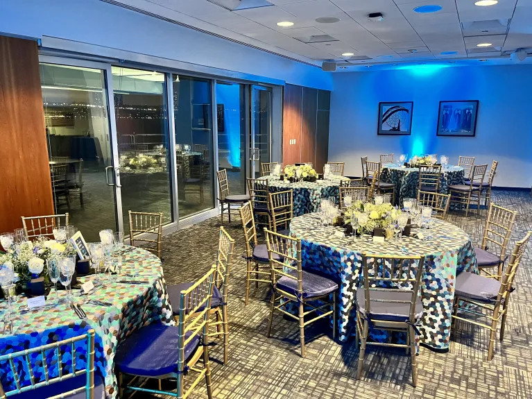 Seated dinner in the VIP Room with blue uplighting and table linens