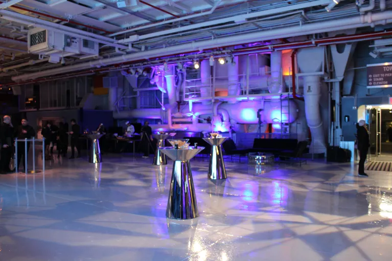Hangar 1 cocktail reception with silver high top tables, uplighting, and lounge furniture