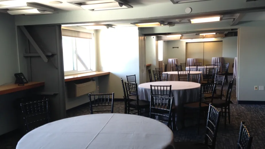 Classrooms set for an event with round tables, linen and black ballroom chairs